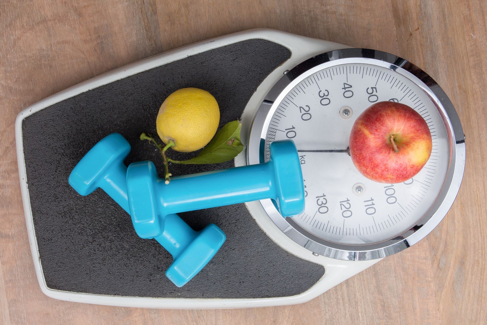 In a bathroom a scale with apple and sport dumbbell